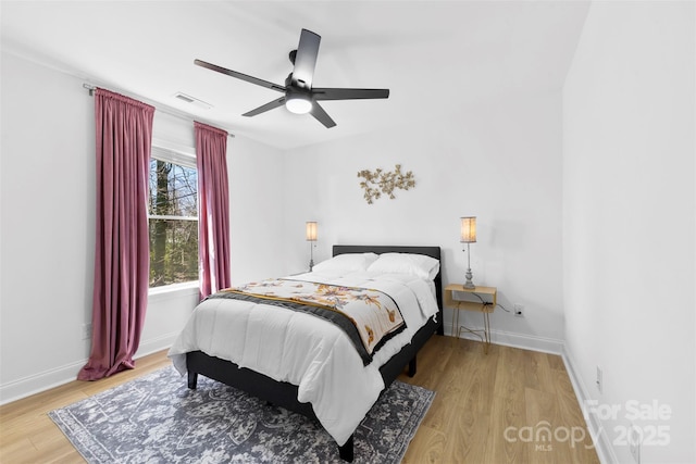 bedroom featuring ceiling fan, visible vents, baseboards, and light wood-style flooring