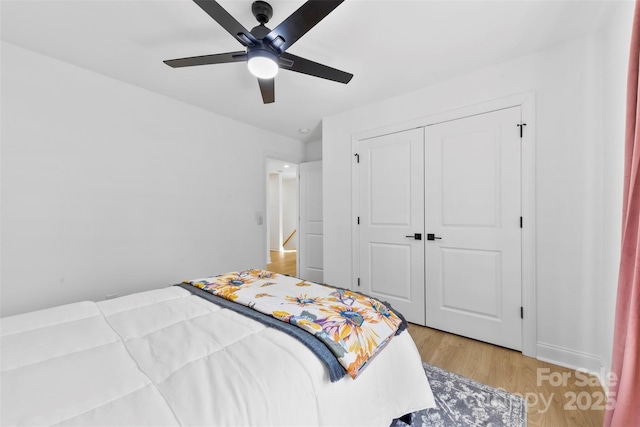 bedroom with a ceiling fan, light wood-type flooring, a closet, and baseboards