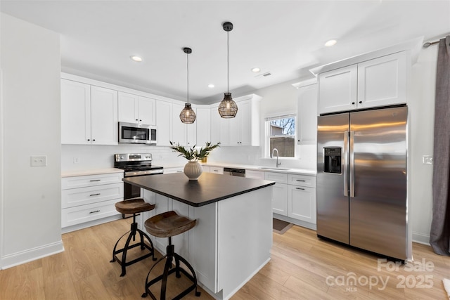 4114 Rutgers Ave, Charlotte, NC 28206 - kitchen featuring appliances with stainless steel finishes, a sink, white cabinetry, a kitchen breakfast bar, and recessed lighting