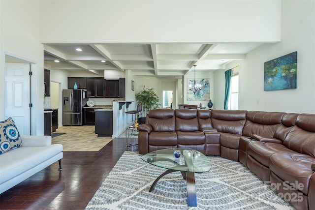 living room featuring beamed ceiling, wood finished floors, coffered ceiling, and a chandelier