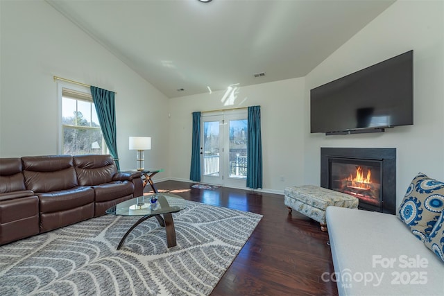 living area with visible vents, wood finished floors, a glass covered fireplace, baseboards, and vaulted ceiling