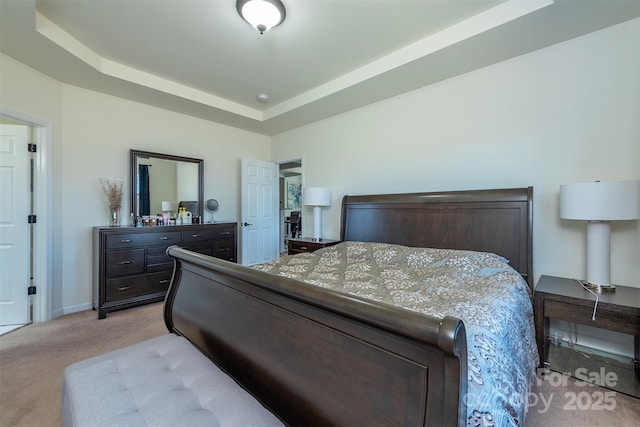 bedroom with a tray ceiling, light colored carpet, and baseboards