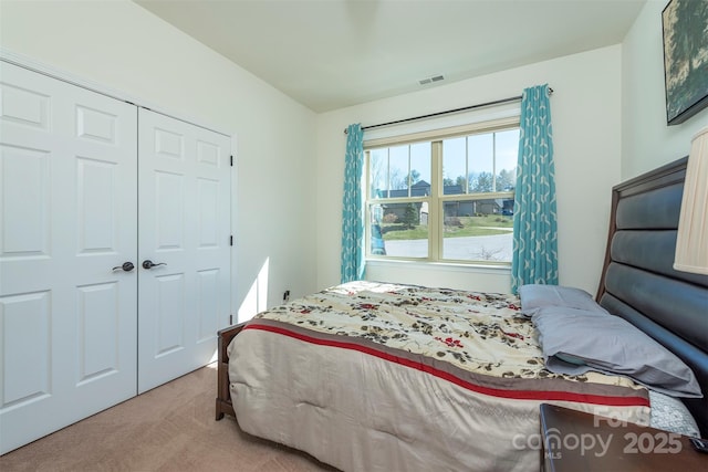 bedroom featuring a closet, visible vents, and light colored carpet