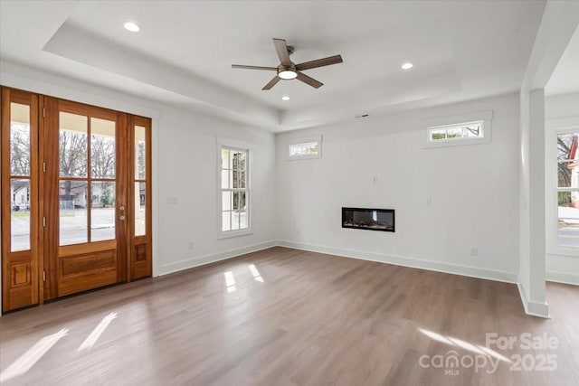 foyer with a raised ceiling, wood finished floors, and a wealth of natural light