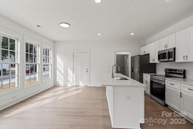 kitchen with recessed lighting, a sink, stainless steel appliances, light countertops, and white cabinetry