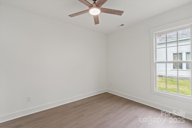 unfurnished room featuring a ceiling fan, visible vents, wood finished floors, and baseboards