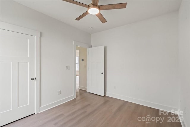 unfurnished bedroom with ceiling fan, baseboards, and wood finished floors