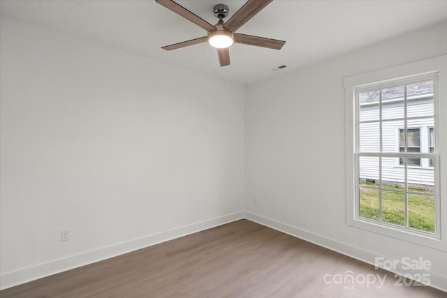 empty room with wood finished floors, baseboards, a wealth of natural light, and ceiling fan