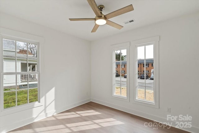 unfurnished room with wood finished floors, baseboards, visible vents, and ceiling fan