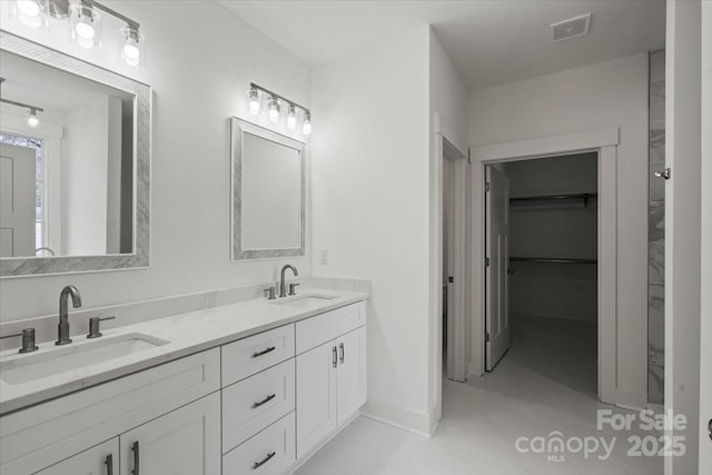 bathroom featuring a sink, visible vents, a walk in closet, and double vanity