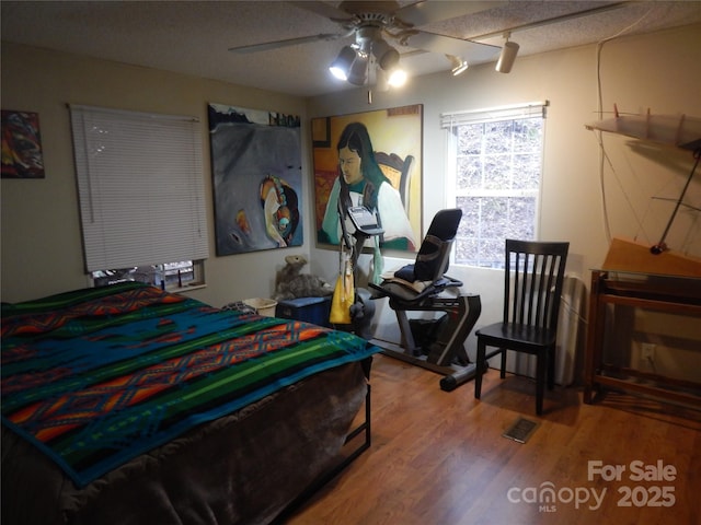 bedroom with visible vents, a ceiling fan, and wood finished floors