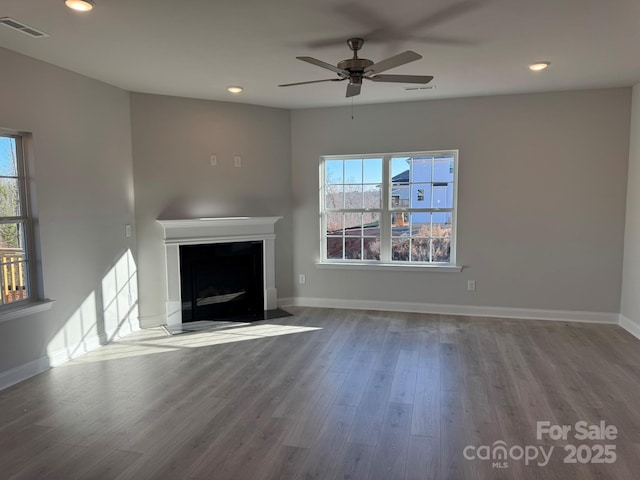 unfurnished living room featuring wood finished floors, visible vents, and a wealth of natural light