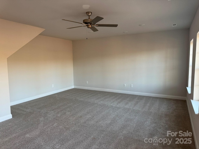 spare room featuring visible vents, a ceiling fan, baseboards, and dark carpet