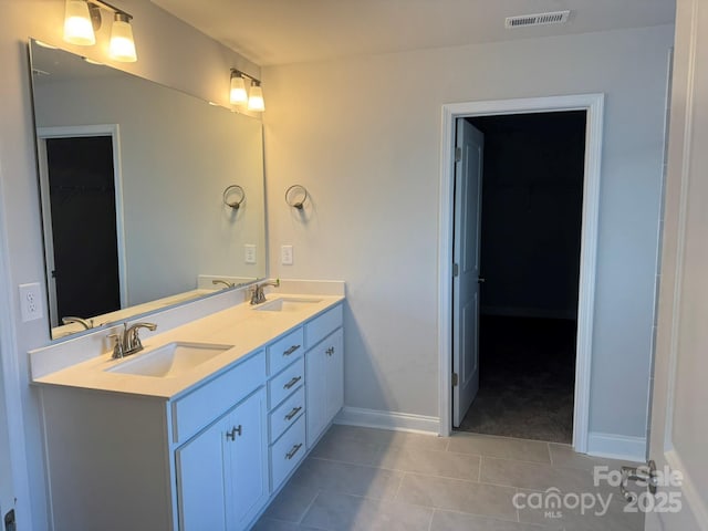 full bathroom featuring double vanity, visible vents, a walk in closet, and a sink