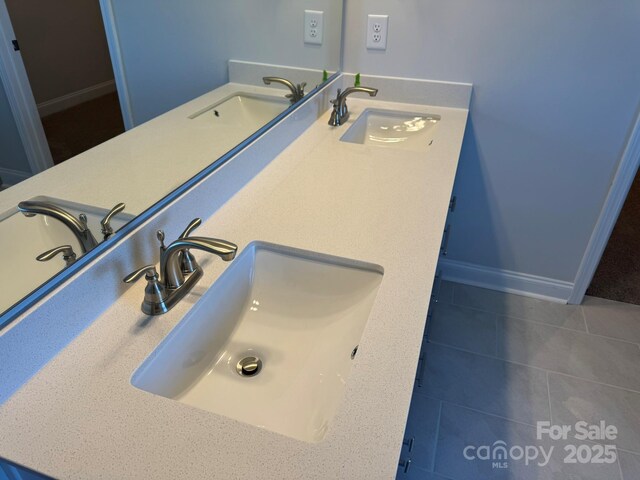 full bathroom featuring double vanity, baseboards, and a sink