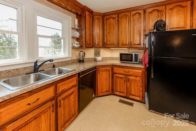 kitchen featuring brown cabinetry, visible vents, a sink, and black appliances