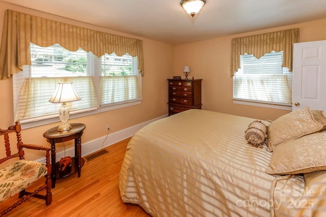 bedroom featuring visible vents, baseboards, and wood finished floors