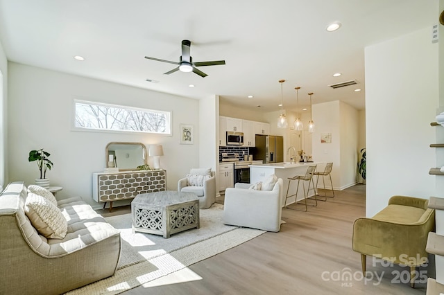 living area featuring recessed lighting, visible vents, ceiling fan, and light wood finished floors