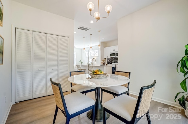 dining room with light wood-type flooring, visible vents, a notable chandelier, recessed lighting, and baseboards