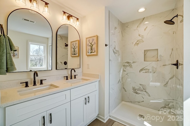 full bath featuring double vanity, visible vents, a marble finish shower, and a sink