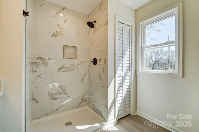 bathroom featuring wood finished floors and a marble finish shower