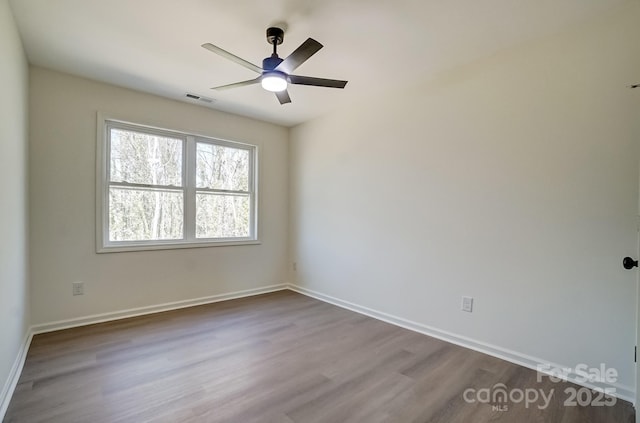 unfurnished room featuring visible vents, baseboards, ceiling fan, and dark wood finished floors