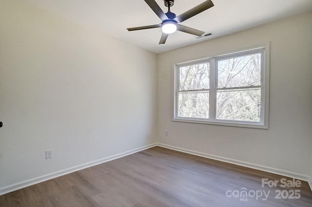 unfurnished room with visible vents, baseboards, dark wood-style floors, and ceiling fan