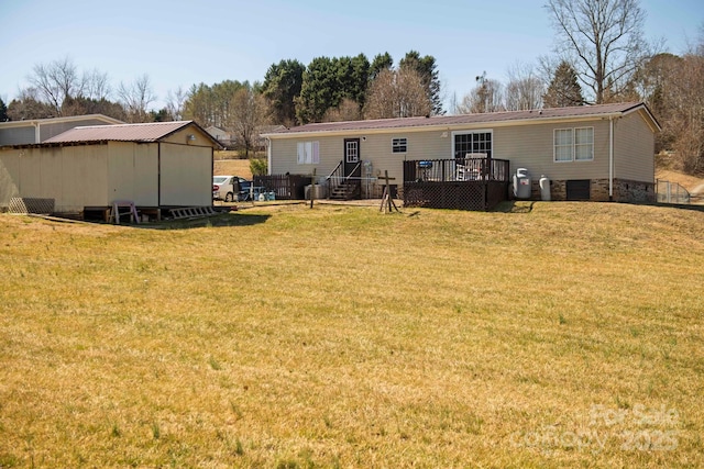 back of property with a wooden deck, a lawn, and metal roof