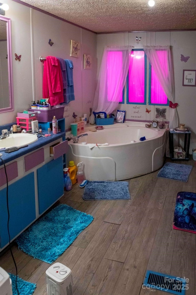 bathroom featuring a bath, a textured ceiling, vanity, and wood finished floors