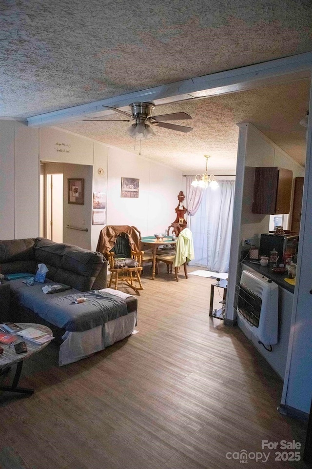 living room with heating unit, wood finished floors, vaulted ceiling with beams, and a textured ceiling