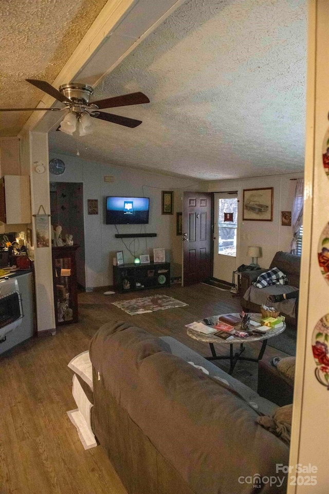 living room with lofted ceiling, a textured ceiling, wood finished floors, and a ceiling fan