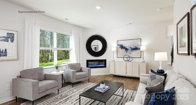 living area with recessed lighting, baseboards, wood finished floors, and a glass covered fireplace