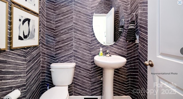 half bathroom featuring tile walls and toilet