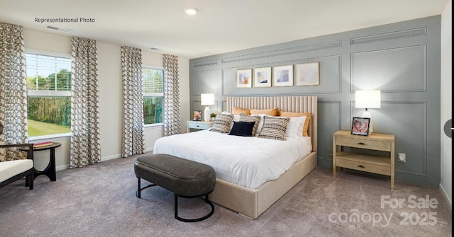 carpeted bedroom featuring a decorative wall, baseboards, and visible vents