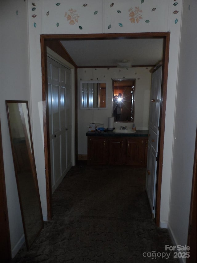 corridor featuring dark carpet and a sink