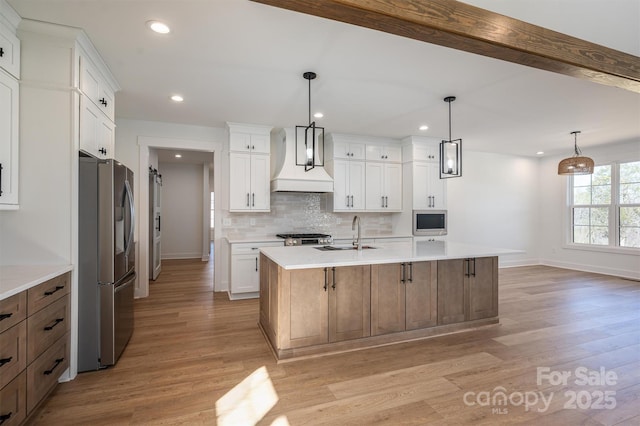 kitchen featuring tasteful backsplash, light wood-style flooring, appliances with stainless steel finishes, and a sink
