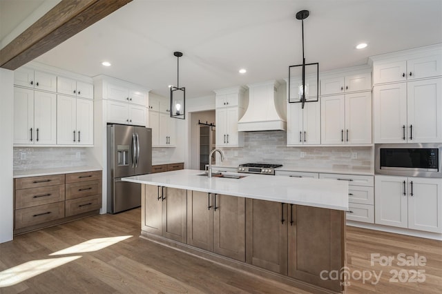 kitchen with a sink, stainless steel appliances, custom exhaust hood, and wood finished floors