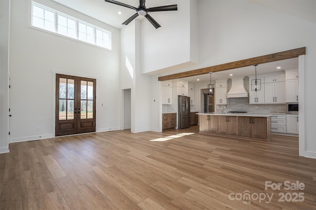 unfurnished living room featuring baseboards, recessed lighting, ceiling fan, french doors, and light wood-style floors