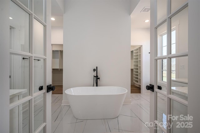 bathroom featuring a soaking tub, marble finish floor, a walk in closet, and visible vents