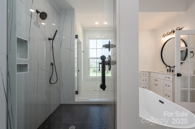 full bath with a marble finish shower, a freestanding bath, and vanity