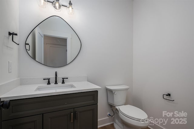 bathroom with vanity, toilet, and baseboards