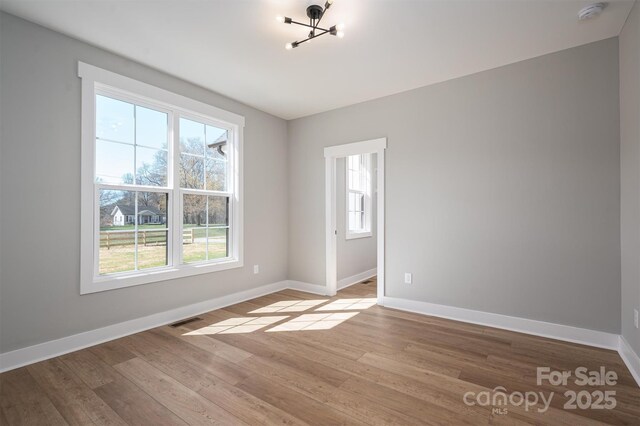spare room with visible vents, baseboards, and light wood-style flooring