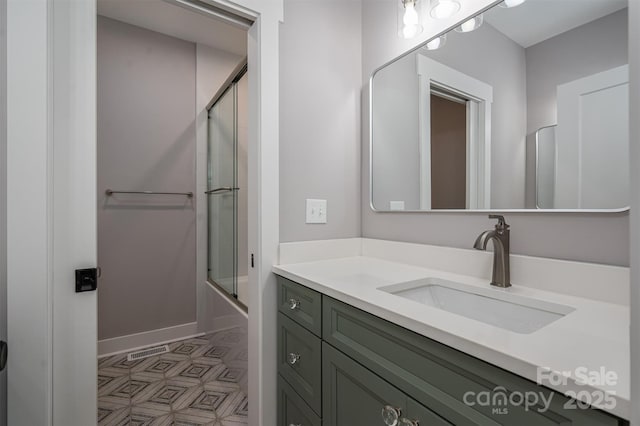 full bath featuring vanity, baseboards, and combined bath / shower with glass door