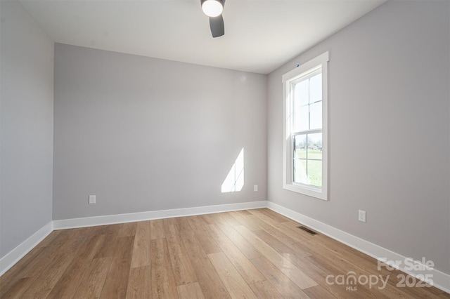 empty room with visible vents, baseboards, light wood finished floors, and ceiling fan