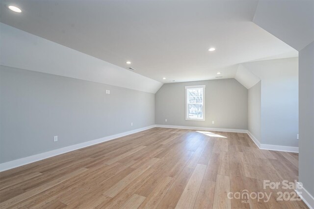 additional living space featuring recessed lighting, baseboards, light wood-style floors, and vaulted ceiling