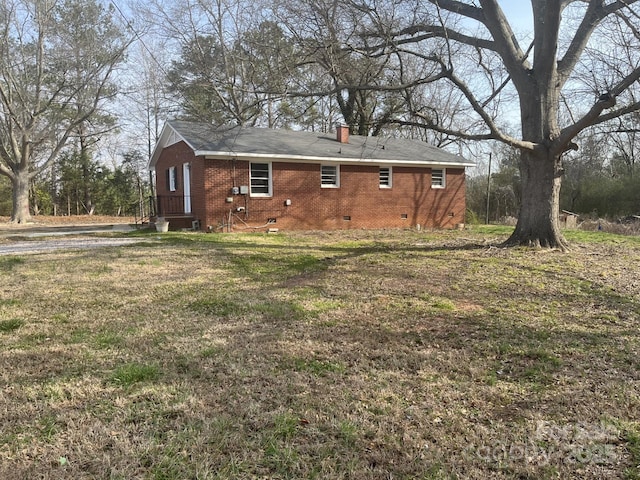 view of side of property featuring a yard, a chimney, and crawl space