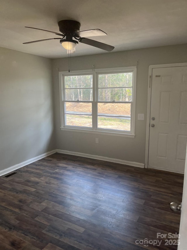 spare room with dark wood-style floors, visible vents, plenty of natural light, and ceiling fan