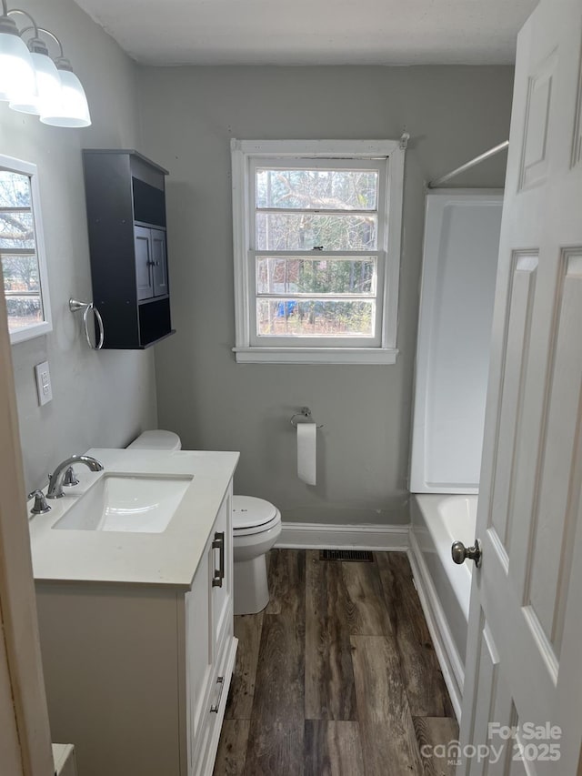 full bath with tub / shower combination, baseboards, toilet, wood finished floors, and vanity