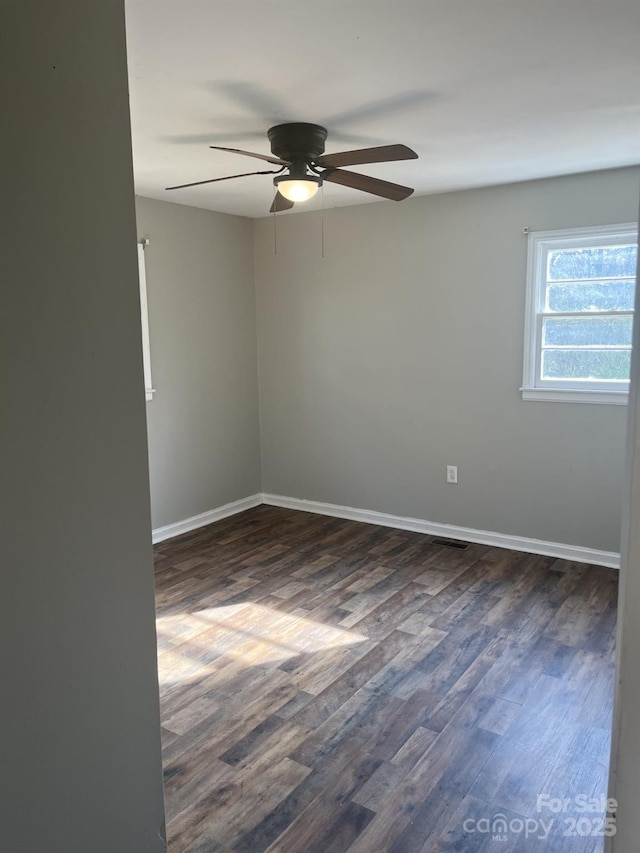 spare room with dark wood finished floors, baseboards, and ceiling fan