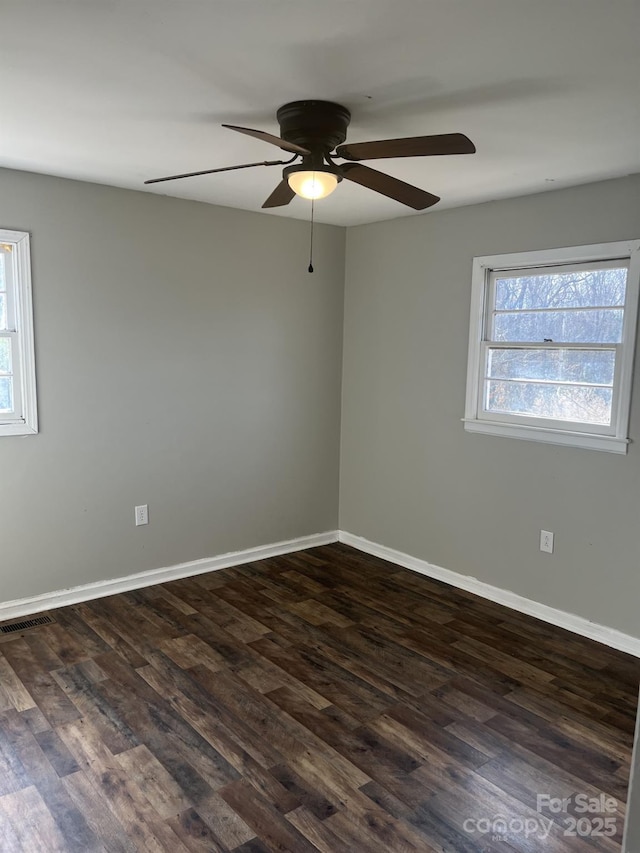 empty room with dark wood finished floors, visible vents, baseboards, and ceiling fan